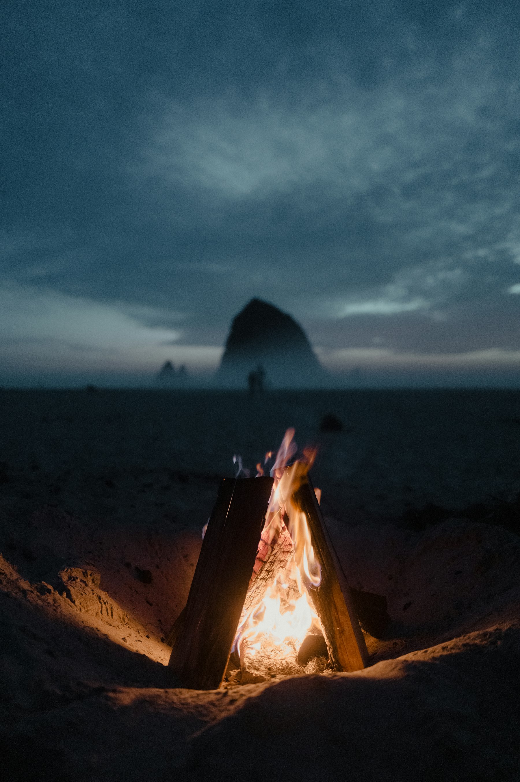 Beach campfire glowing at dusk
